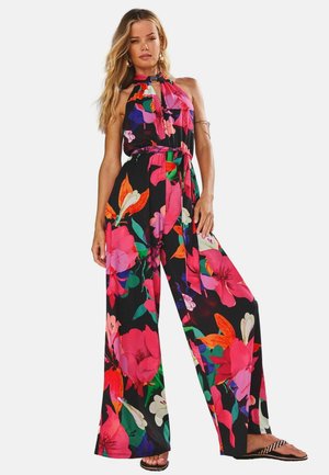 Jumpsuit floreale con colletto alto e chiusura a occhio di bue, in nero con fiori rosa acceso, arancioni e verdi; gambe larghe e cintura coordinata.