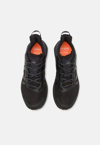 Scarpe da ginnastica nere con tomaia in rete, superficie texturizzata e lacci grigi. Presentano un anello sul tallone e una soletta arancione.