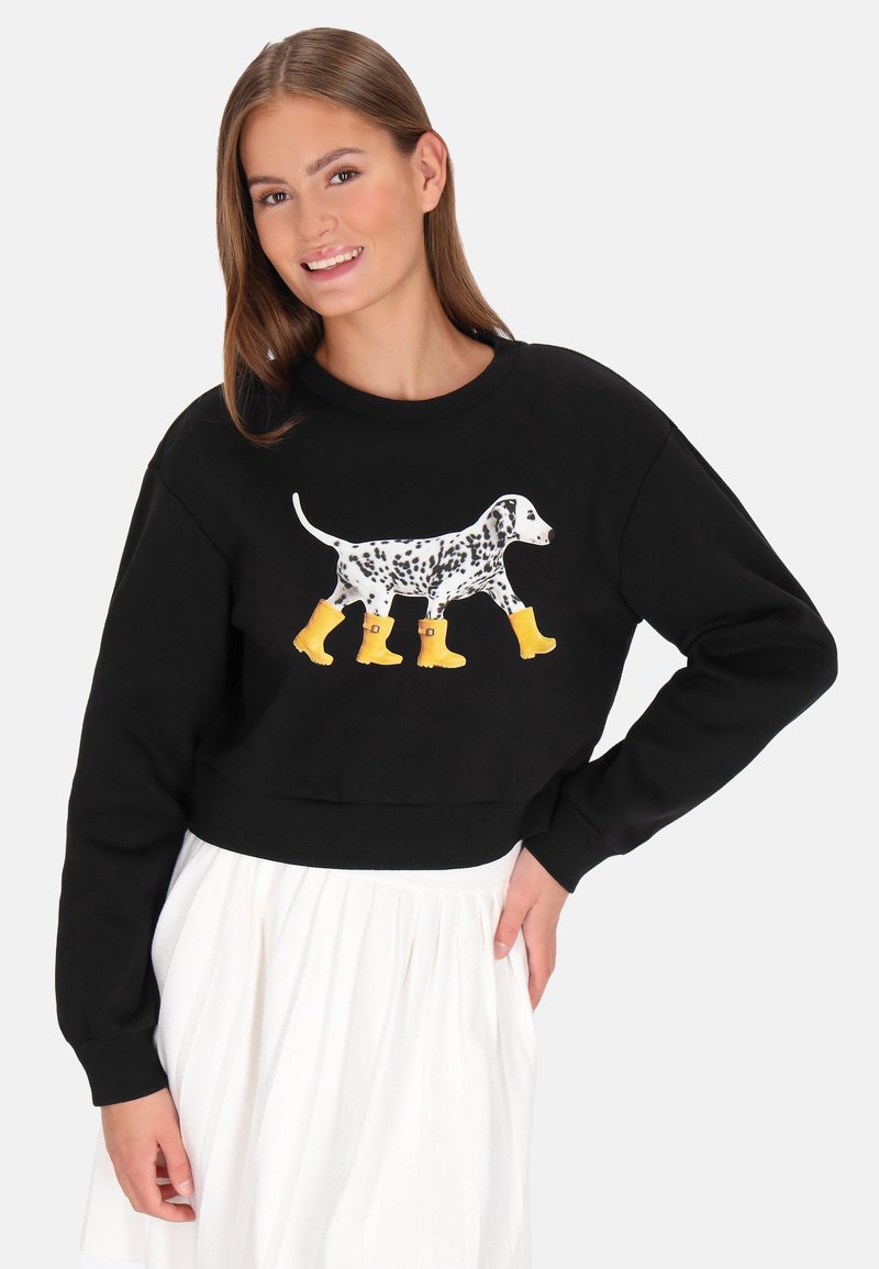 Sudadera negra corta con un diseño de dálmata blanco que lleva botas de lluvia amarillas. Cuenta con un cuello redondo y puños acanalados.