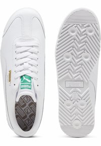 Fehér bőr sneaker cipők lapos fűzőkkel, párnázott talpbetéttel, amely geometrikus mintával rendelkezik, és texturált gumitalppal, amely halszálkás mintát mutat.