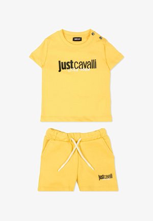 Żółty zestaw dla malucha składający się z topu z krótkim rękawem i krótkich spodenek z elastycznym pasem, oba z logo "Just Cavalli Little Rogue" w czerni i bieli.