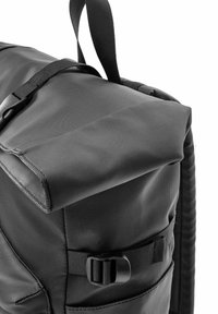 Czarny plecak z teksturowanej tkaniny z klapą na górze, regulowanym paskiem i zapięciem na klamrę z boku.