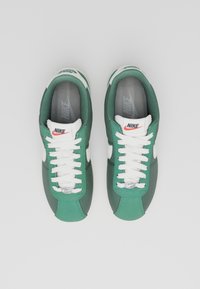 Gröna och grå Nike-sneakers med vita detaljer, med snörningsdesign, vadderad krage och en texturerad ovandel för bättre grepp.