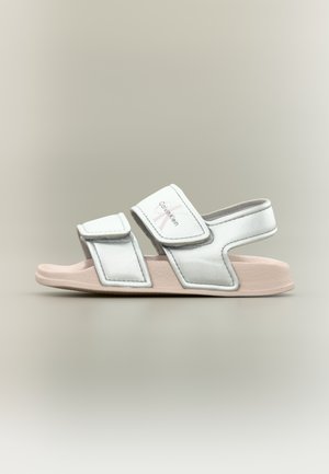 Hvite og lyserosa Calvin Klein sandaler med åpen tå, to justerbare stropper og polstret såle, vist fra siden.