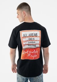 Black t-shirt featuring a colorful graphic on the back with the text "ALL AREAS," "OASIS," and "London 16th Aug," and a red-orange design.