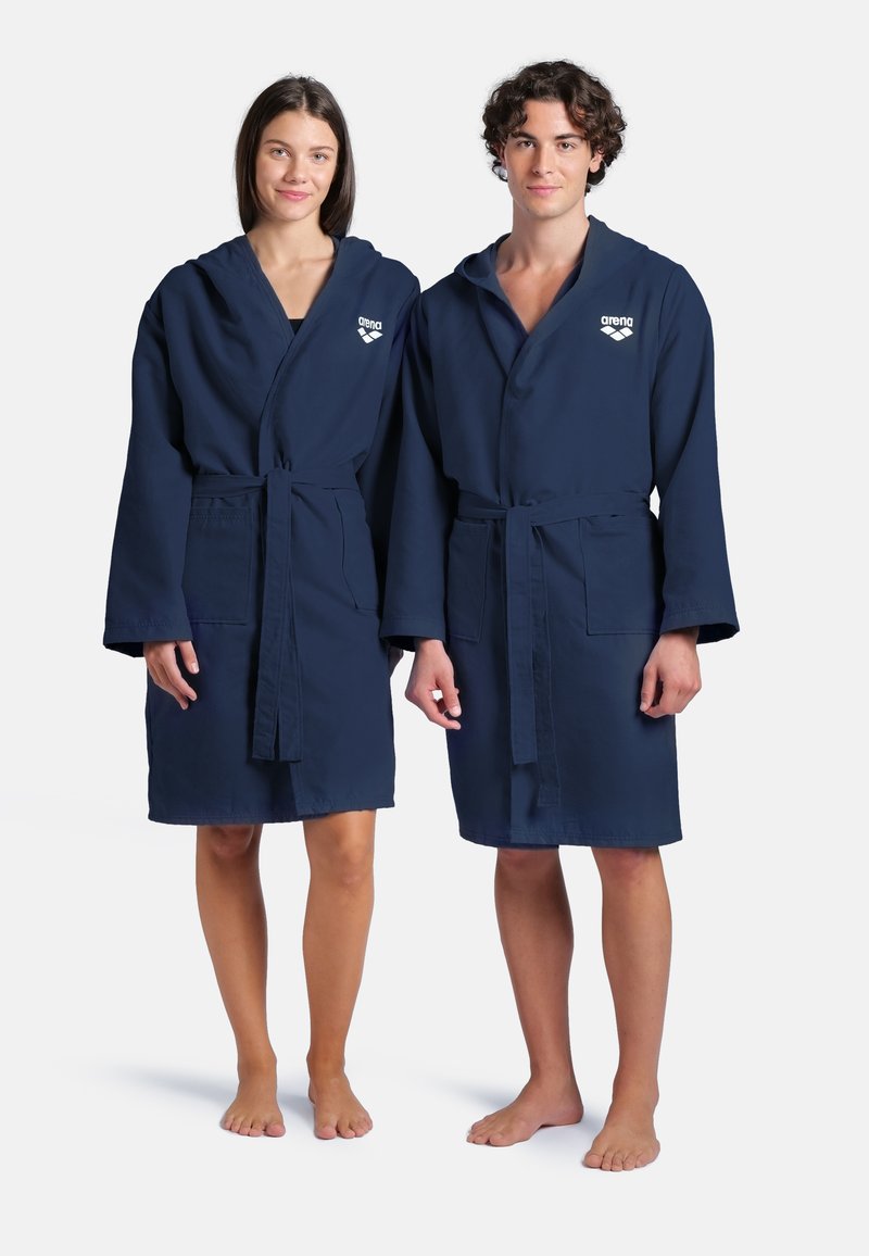 Accappatoi con cappuccio color blu navy realizzati in morbido tessuto, dotati di cintura a tie, maniche ampie e tasche frontali. Logo Arena visibile sul petto.