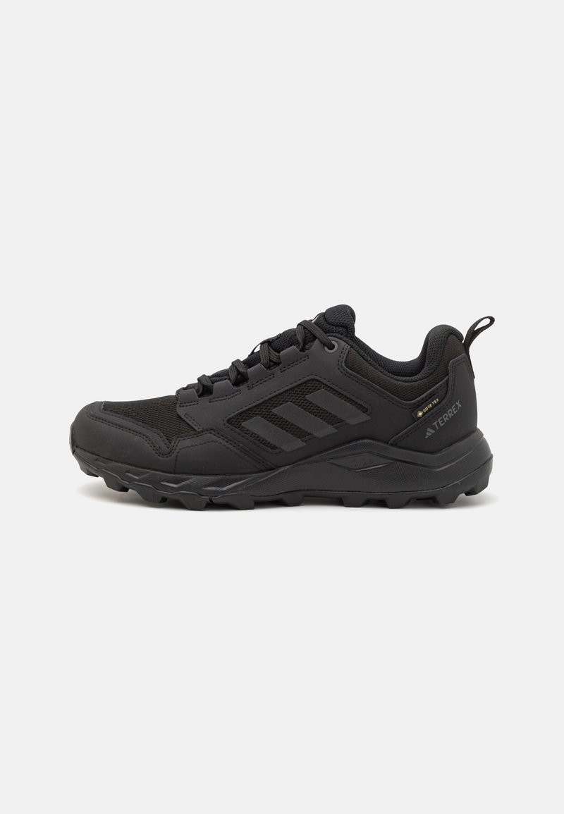 Black athletic shoes with a sturdy rubber sole, mesh and synthetic upper, pronounced lacing system, and a pull tab at the heel.