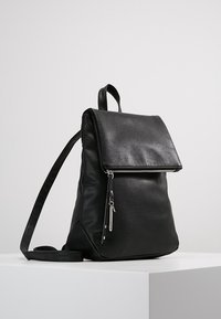 Czarny skórzany plecak z klapką na złożenie, srebrnym suwakiem, regulowanymi paskami na ramiona i gładką, teksturowaną powierzchnią.