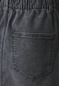Pantaloni di denim neri con elastico in vita, dotati di una tasca posteriore, caratterizzati da una sottile texture stone-washed.