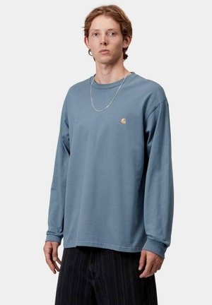 Camisa de manga larga azul hecha de algodón, con cuello redondo, logo sutil en el pecho y corte relajado con puños acanalados.