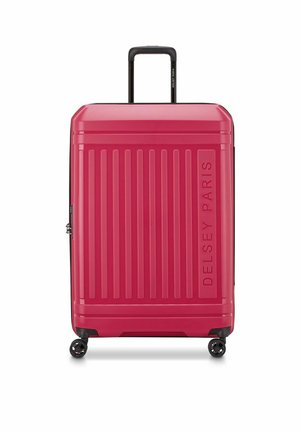 Harde roze koffer met verticale groeven, bovenhandvat en vier zwarte wielen. Kenmerkt het logo "DELSY PARIS" dat aan de zijkant is geperst.