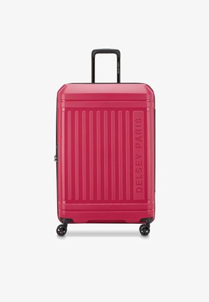 Harde roze koffer met verticale groeven, bovenhandvat en vier zwarte wielen. Kenmerkt het logo "DELSY PARIS" dat aan de zijkant is geperst.