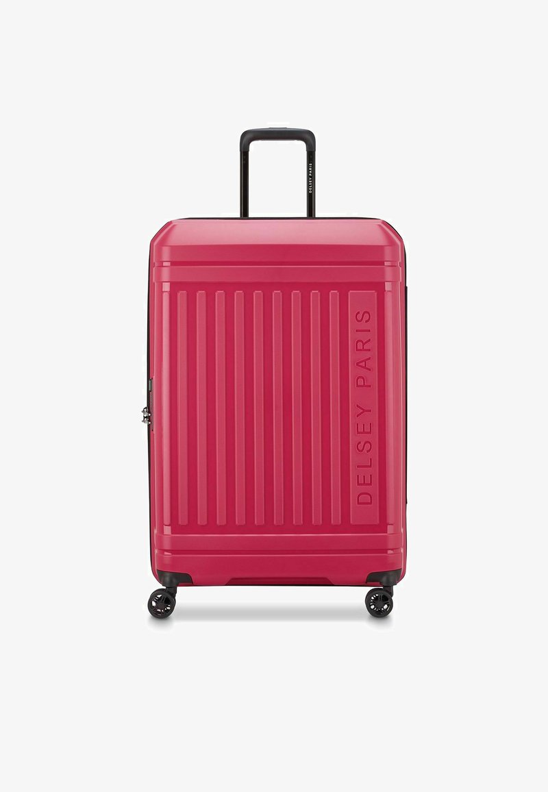 Maleta rígida rosa con surcos verticales, asa superior y cuatro ruedas negras. Presenta el logo "DELSY PARIS" grabado en el lateral.