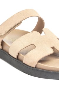 Beige Wildledersandale mit einer schwarzen Gummisohle, die ein offenes Design und einen breiten Zehenriemen mit Ausschnitten aufweist. Mit Klettverschluss einstellbar.