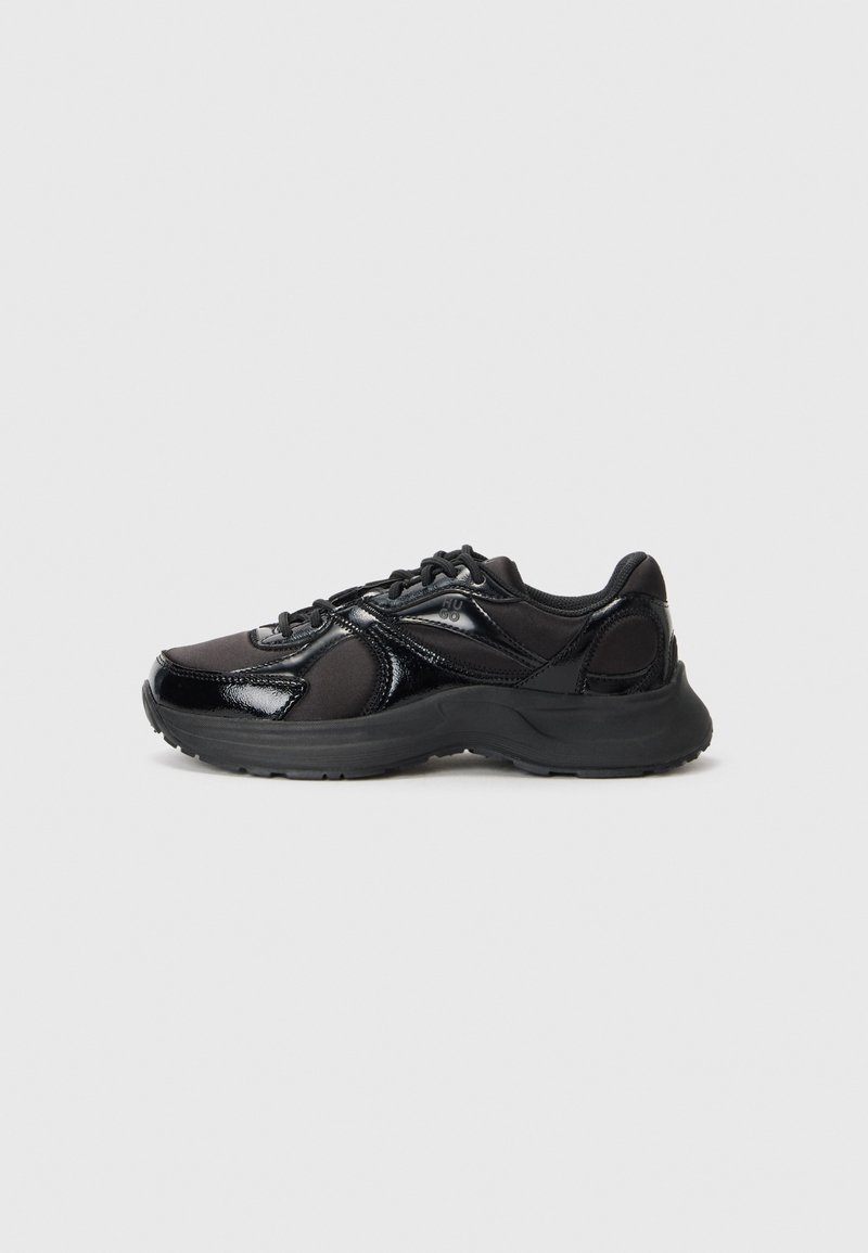 Baskets de sport noires avec un mélange de textures brillantes et mates, fermeture à lacets, semelle de soutien et design épuré.