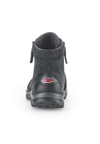 Black suede ankle boot with rounded toe, padded collar, zip closure, and textured rubber sole. Features a red and white logo detail.