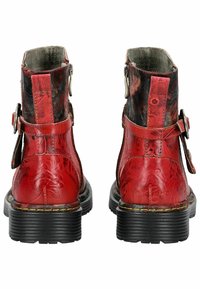 Stivali alla caviglia in pelle rossa con embossing floreale, punta rotonda e suola in gomma nera spessa. Presenta una tracolla laterale regolabile e accessori in metallo.