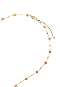 Złoty naszyjnik z łańcuszka z małymi gwiazdkami i okrągłymi koralikami. Gwiazdy mają brązowy odcień, co dodaje kontrastu do błyszczącego złota.