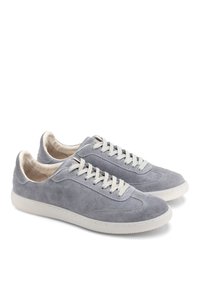 Hallikad nahk-sneakerid heledate hallide paeltega, ümarate varvastega ja valge kummitald. Sile tekstuur ning peened õmblemise detailid küljel.