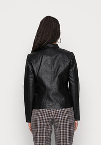 Black leather jacket with a tailored fit, notched collar, and visible seam detailing, paired with checkered pants.