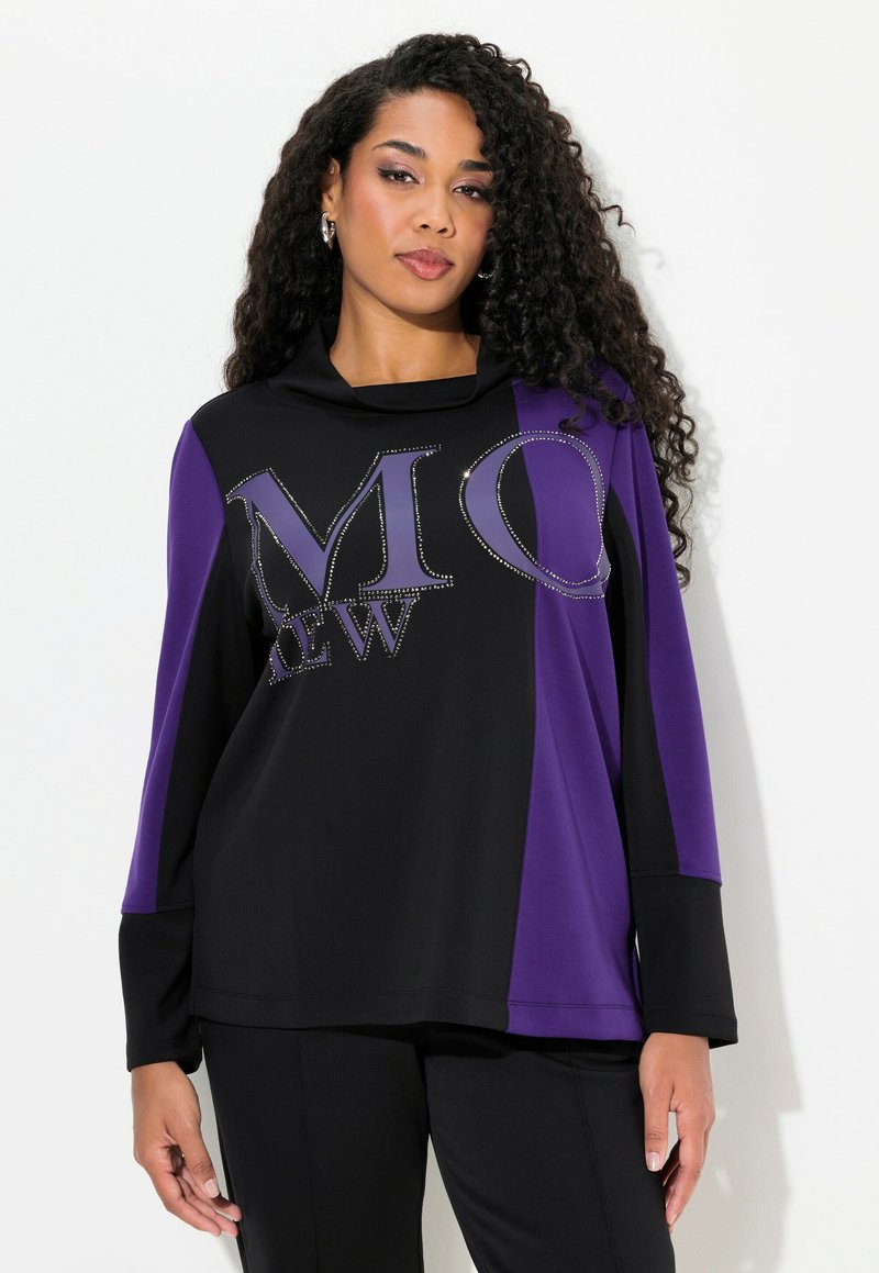Svart och lila långärmad topp med cowl-halsringning, prydd med en stor "MO"-grafik dekorerad med rhinestones. Slät, mjuk tygtextur.