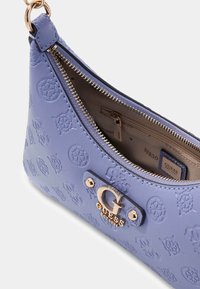 Jasnoniebieska torebka z ekoskóry z tłoczonym kwiatowym wzorem, złotymi okuciami i zamknięciem na zamek. Wnętrze zawiera metkę marki.