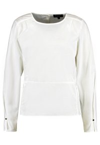 Camicia bianca a maniche lunghe con scollo rotondo e orlo arrotondato. Presenta un tessuto liscio, cuciture sottili e bottoni decorativi sui polsini.