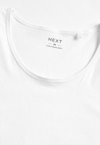 Weißes Baumwoll-T-Shirt mit Rundhalsausschnitt, das hinten am Hals ein Etikett mit der Aufschrift "NEXT M" und "MADE IN BANGLADESH" trägt.
