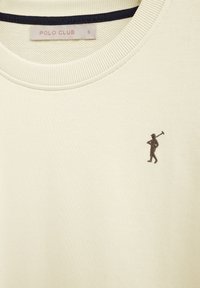 Cream-colored crewneck shirt with small dark brown polo player embroidery and a size small "POLO CLUB" label inside collar.