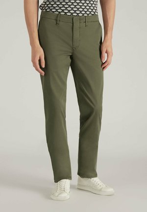 Pantalones de algodón color verde oliva con un corte regular, que presentan bolsillos frontales, cremallera y una textura suave. Combinados con zapatillas blancas.
