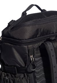 Czarny plecak z teksturowanej tkaniny, z zamykanymi kieszeniami, regulowanymi paskami i wytrzymałym uchwytem na górze. Zawiera detale siatkowe.