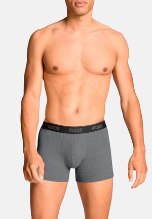 Graue Boxershorts mit einem schwarzen elastischen Bund, der das Puma-Logo trägt. Der Stoff wirkt glatt und eng anliegend, entworfen für Komfort und Unterstützung.