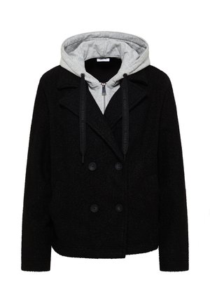 Abrigo negro de doble botonadura con textura, superpuesto a una sudadera gris con cremallera, capucha y cordones negros.
