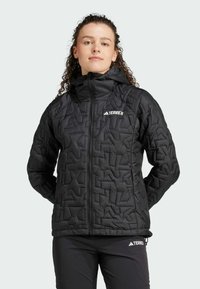 Veste noire rembourrée avec un design matelassé géométrique, fermeture éclair et capuche. Présente le logo Terrex sur la poitrine et sur le pantalon.
