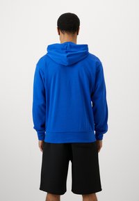 Μπλε hoodie με καπελάκι με κορδόνι, ριχά μανίκια και στρίφωμα, υφασμάτινη υφή, σε συνδυασμό με μαύρα σορτς. Απλό, σχέδιο χαλαρού στυλ.
