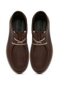 Scarpe in pelle marrone con finitura testurizzata, dotate di lacci incrociati e cuciture a contrasto, presentate da una vista dall'alto.