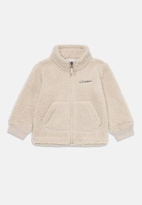 Veste en polaire beige clair avec col haut, fermeture éclair à l'avant, deux poches et poignets côtelés, arborant le logo Columbia en haut à gauche.