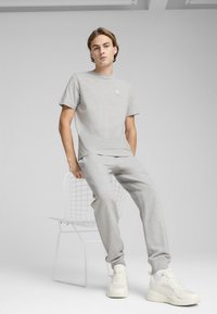 Šedé bavlněné tričko a odpovídající tepláky s minimalistickým designem, malý logem na tričku a texturované tenisky.