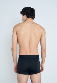 Fekete boxer alsónadrág sima textúrával és széles derékpánttal, minimalista kialakítással, minta és látható fémszerelvények nélkül.