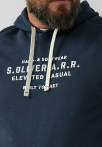 Granatowy polar z bawełny, z kapturem i sznureczkiem w kolorze kremowym, z białym nadrukiem przedstawiającym markę i styl.