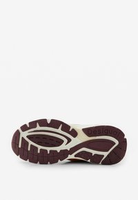 Suela de una zapatilla deportiva con dibujo en burdeos y blanco, que presenta el nombre de la marca "Desigual" en la zona del talón.