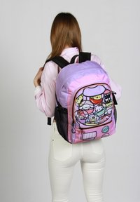 Mochila multicolor con un diseño en morado y rosa, que presenta estampados de personajes de dibujos animados, bolsillos laterales de malla negra y dos correas negras.