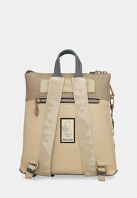 Zaino beige texturizzato realizzato in materiale sintetico con spallacci grigi, dotato di tasca frontale con zip, badge con logo e charm decorativo.