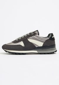 Graue Sportschuhe mit einem Design aus Wildleder und Satin, ausgestattet mit einer dicken Sohle, Schnürung vorne und einem Logo an der Ferse.