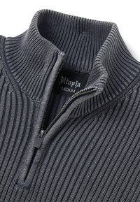 Donkergrijze geribbelde pullover met een hoge hals en halve ritssluiting. Beschikt over een soepele textuur en een label waarop maat medium staat.