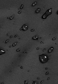 Water droplets on a dark gray fabric, showcasing a smooth texture and a subtle sheen, indicating water resistance.