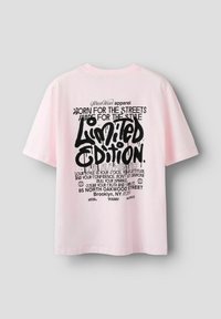 Roze katoenen t-shirt met gedurfde zwarte grafische tekst op de achterkant, met de tekst "Limited Edition" en verschillende artistieke zinnen. Korte mouwen.