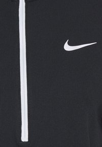 Černý žebrovaný atletický top s vysokým límcem, vybavený bílým zipem a malým bílým logem Nike na hrudi. Měkká textura.