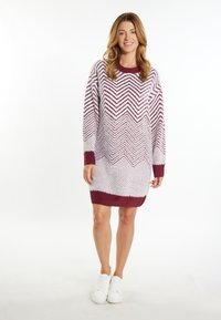 Rochie supradimensionată din lână albă cu model zigzag în nuanță de merișor. Guler și mansete ribbate, textură moale, design până la genunchi. Purtați cu adidași albi.