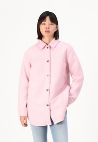 Pink wool blend jacket featuring a collar, button front closure, and side pockets. Long sleeves with a relaxed fit and smooth texture.